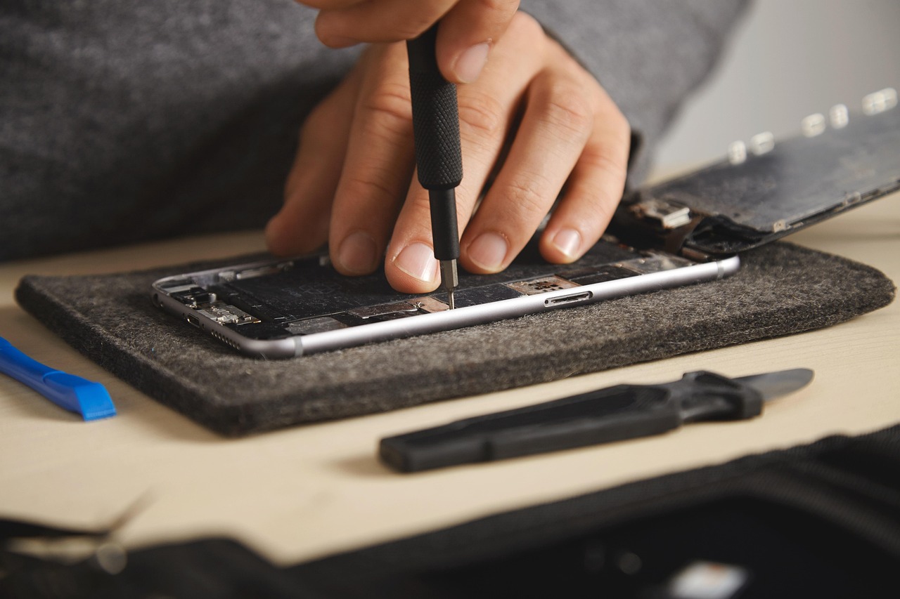 A person carefully opening a device with a precision screwdriver during a repair