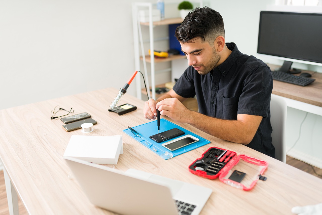 A repair technician carefully working on a device at a tidy, well-lit workbench